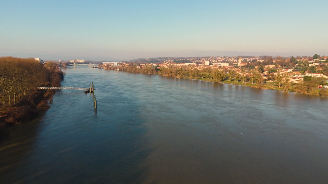 Villefranche-sur-Saone,Rhone,France flight along the majestic River Saone with the town and bridges beyond past riverside walks and jetties in golden sun with clear blue sky