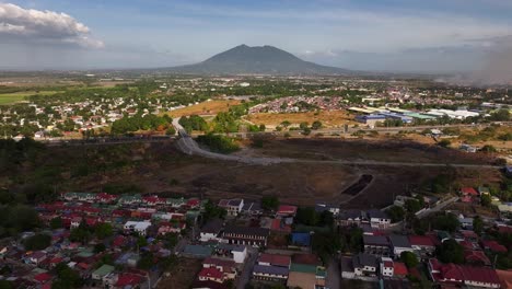 drone panorama of rural asian neighborhood, approaching highway and giant mountain in background