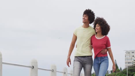 Afroamerikanisches-Junges-Paar-Umarmt-Sich-Beim-Gemeinsamen-Spaziergang-Auf-Der-Promenade-In-Strandnähe