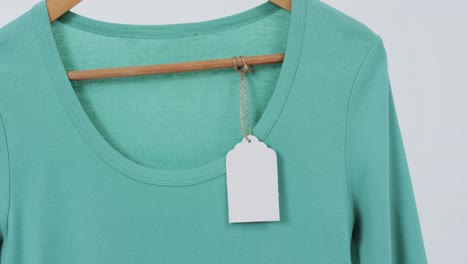 Video-of-green-t-shirt-with-tag-on-hanger-and-copy-space-on-white-background