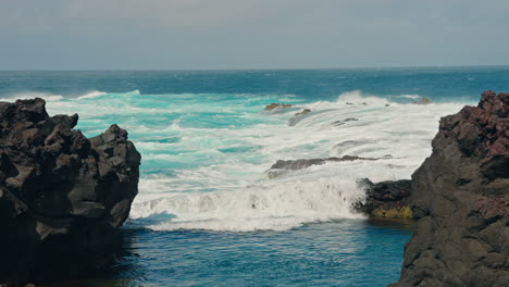 Slow-motion-shot-of-rough-ocean-waves-crushing-against-the-volcanic-rocky-coastline