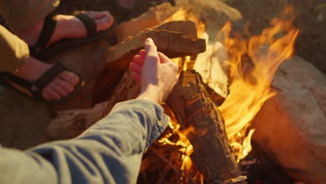 closeup of feet and hands near a campfire