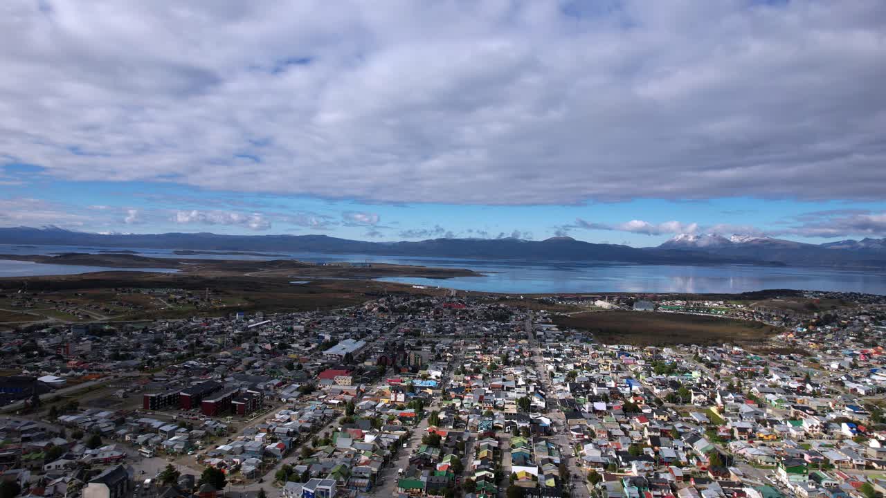 Aerial Drone Footage Captures Ushuaia Village In Argentina, Showcasing Small Houses Near The Beagle Channel. The Blue Water Reflects The Sky On A Cloudy Summer Day in 4K