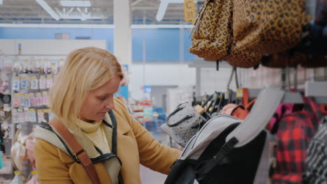 a woman chooses a school backpack in a store