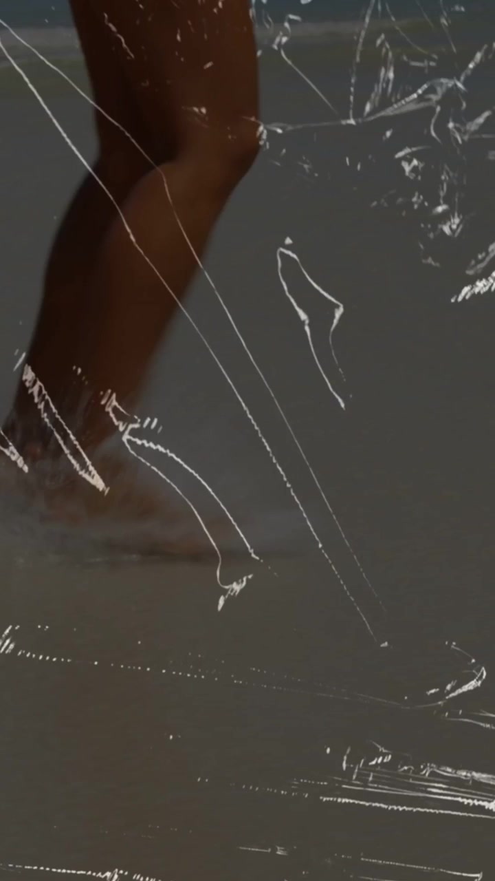 Video verticale: Gambe di donna che camminano, piede che tocca la risacca, overlay graffiato che copre l'inquadratura per il design.