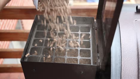 pouring hardwood pellets into the hopper of a smoker to prepare for cooking a meal