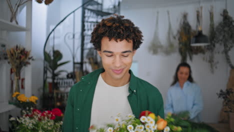 el cliente sonriente disfruta de la compra de flores en la tienda de plantas. el hombre africano sale de la tienda.