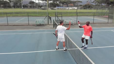 diverse male tennis players holding rackets and playing tennis at court