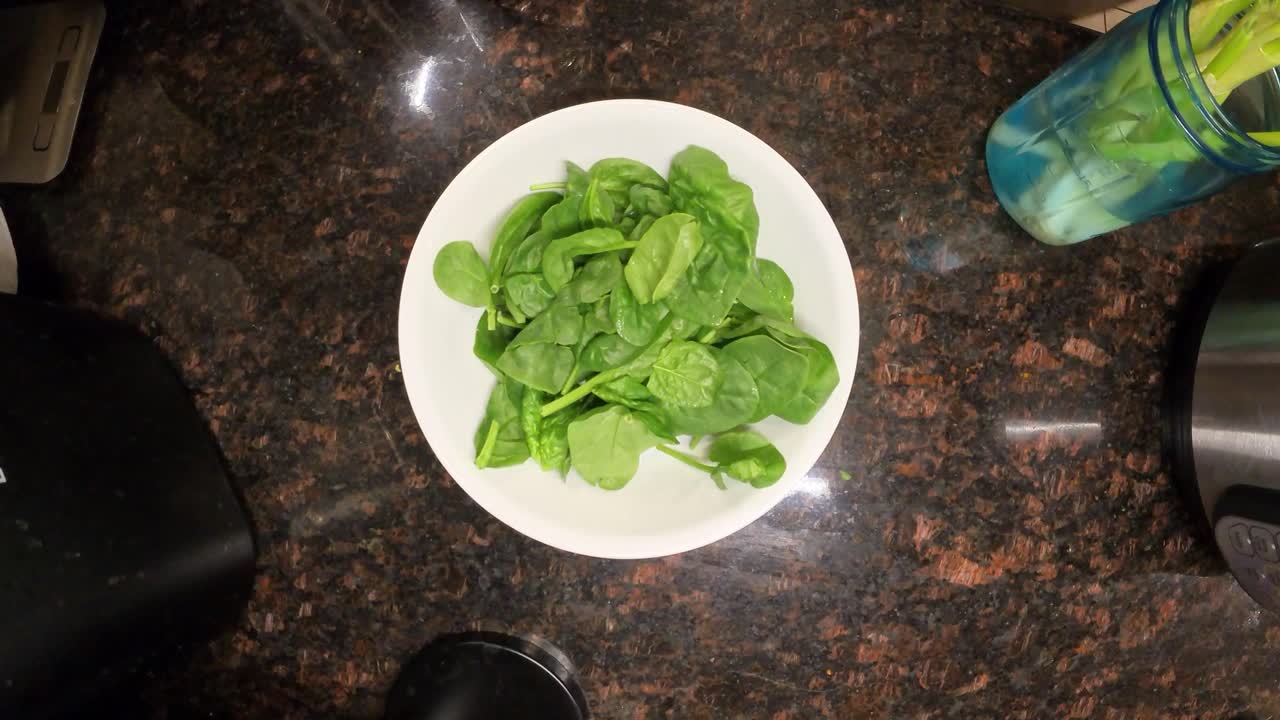 Top view close up footage captures a chef placing fresh spinach leaves onto a plate while preparing coleslaw in kitchen
