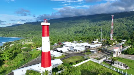 faro rojo y blanco en la frontera de indonesia, papúa nueva guinea, hay montañas y hermosas nubes azules en el cielo