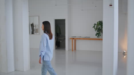 girl crossing modern gallery on weekend. thoughtful visitor looking green plants