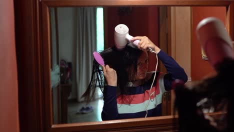 Adult-female-drying-her-hair-with-brush-and-electric-hairdryer