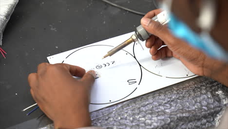 person soldering wires to the back of led panel