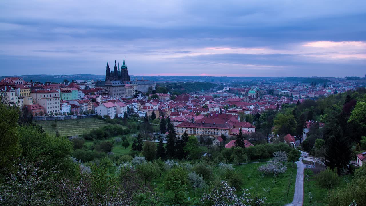 Timelapse do nascer do sol, da noite para o dia, em Praga, República Tcheca, visto dos jardins de Strahov, com vista para o Castelo de Praga, Malá Strana e o centro da cidade ao longe, enquanto o sol da manhã ilumina a cidade