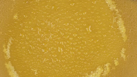 rotation of natural beeswax in raindrops. close-up. natural beeswax melted from honeycomb. beeswax background and texture.