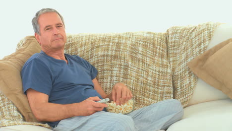 mature man watching tv with popcorn