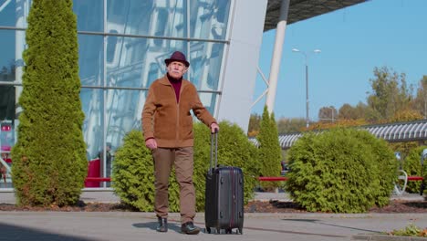 Retired-grandfather-businessman-walking-with-luggage-suitcase-bag-to-airport-hall-or-railway-station