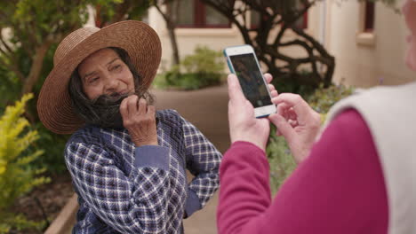 retrato de una anciana feliz bailando posando con un sombrero disfrutando de la jubilación un amigo tomando una foto usando un teléfono inteligente