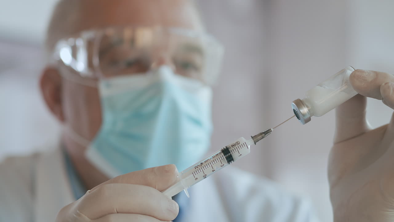 Close up shot of unrecognizable nurse or doctor in gloves filling syringe from ampule with covid-19 vaccine. Nurse filling injection syringe from vial. High quality 4k footage