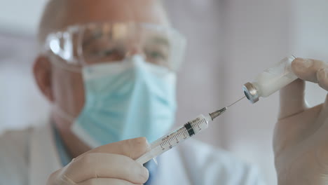 close up shot of unrecognizable nurse or doctor in gloves filling syringe from ampule with covid-19 vaccine. nurse filling injection syringe from vial. high quality 4k footage