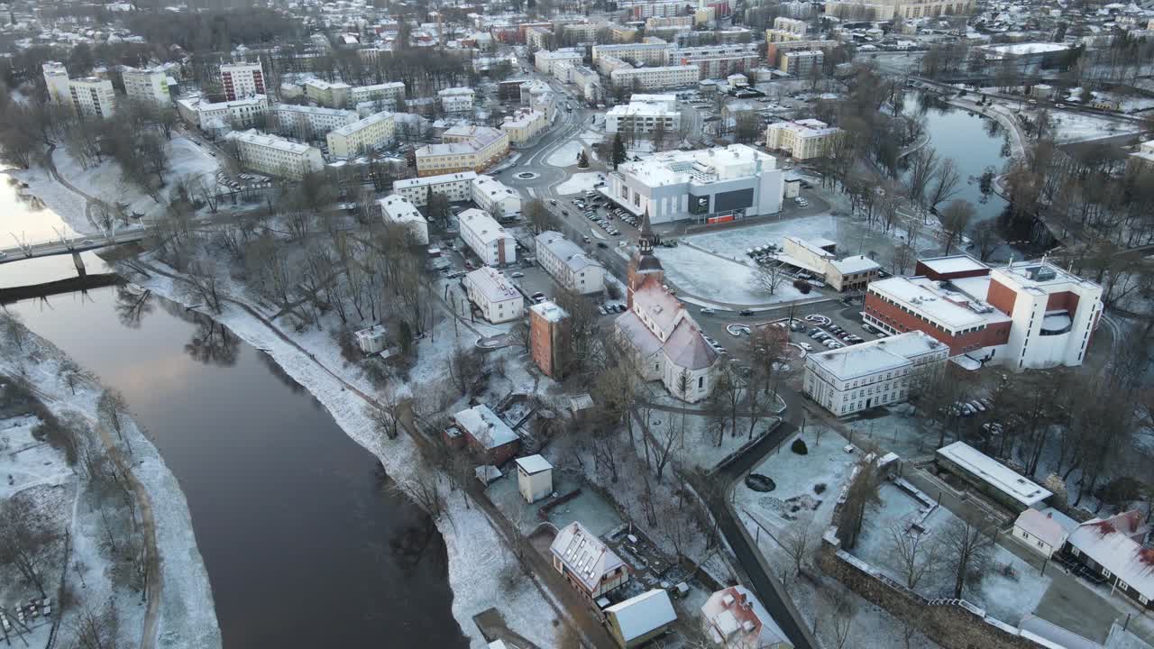 Et betagende luftfoto af byen Valmiera, der viser den snoede Gauja-flod omgivet af snedækkede landskaber og boligområder under en vinterhimmel.