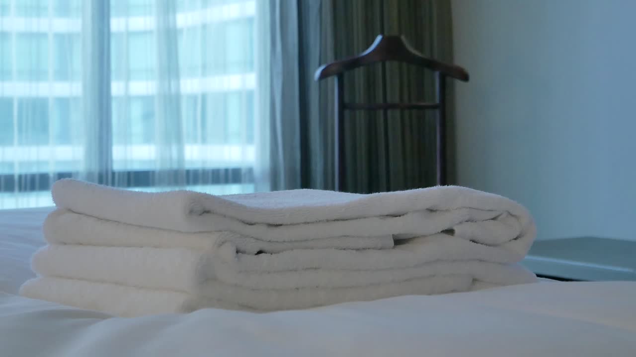 가정부는 방에 있는 침대에 수건을 놓고 있다