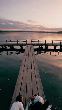 couple lying on a wooden pier at sunset