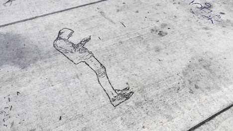 Graffiti-of-a-hooded-man-viewing-a-handheld-device-etched-on-a-concrete-walkway