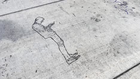 graffiti of a hooded man viewing a handheld device etched on a concrete walkway