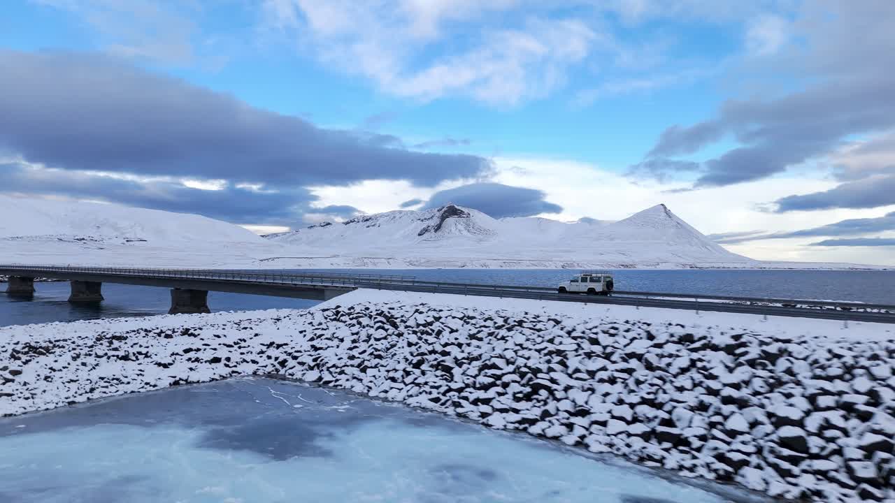 Scenic road highway bridge over water with stunning mountain landscapes covered in snow, Kolgrafafjorour fjord, Drone Shot