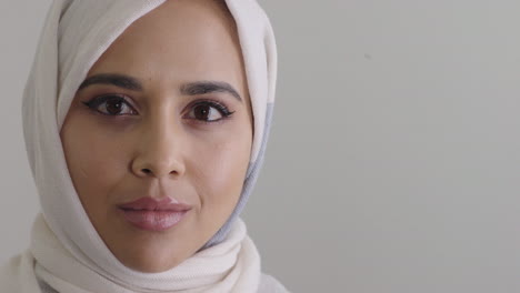 Junge-Muslimische-Frau-Blickt-In-Die-Kamera-Und-Trägt-Ein-Traditionelles-Hijab-Kopftuch-Auf-Leerem-Hintergrund,-Kopierraum-Aus-Nächster-Nähe