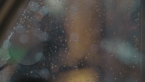 Wet-glass-and-evening-street-with-car-traffic-and-litter-bin