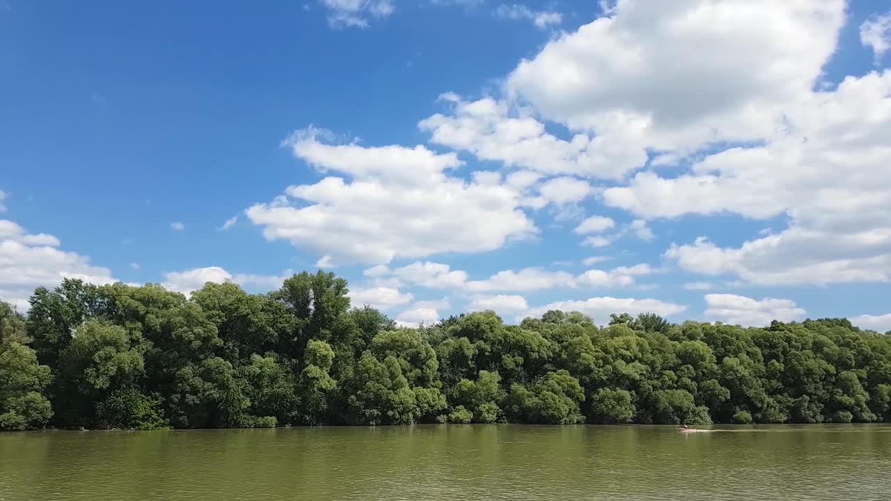 navegando con un bote en un río con nubes esponjosas en un día soleado de verano