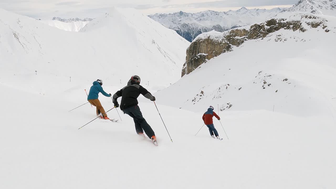 Sci acrobatico cinematografico in bella formazione di tre atleti sciatori in una stazione sciistica in Svizzera su una pista da sci con magnifica vista panoramica sulle montagne