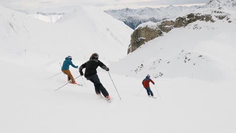 Cinematic-show-skiing-in-nice-formation-of-three-ski-athletes-in-a-ski-resort-in-switzerland-on-a-ski-slope-with-great-panorama-mountain-view