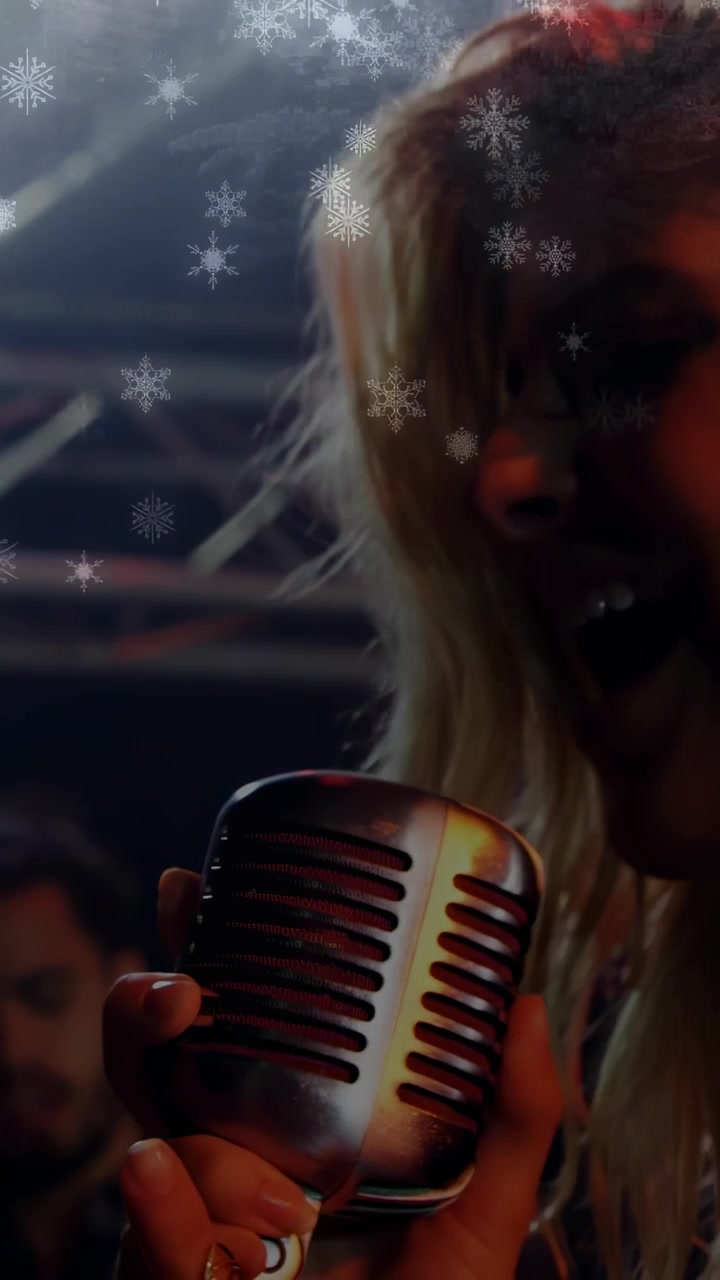 Vertical video: Camera pulling back singer holding retro mic singing snow overlay making music mood
