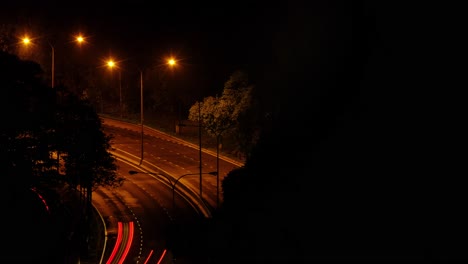 toma amplia nocturna de lapso de tiempo de tráfico en una carretera, vista desde el puente