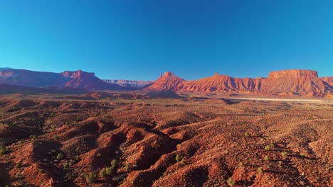 aerial tracking right establishing of moab dramatic rock formations, layered sandstone cliffs glowing under midday sunlight
