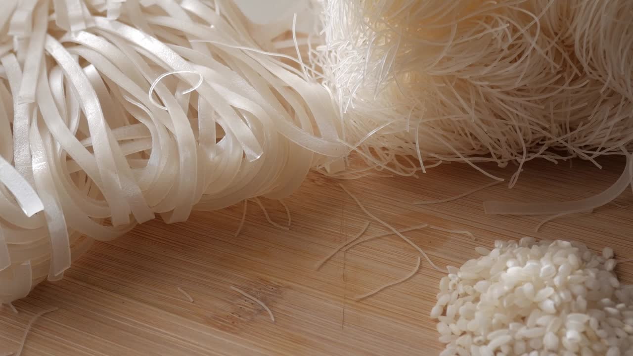 Close-up of rice vermicelli noodles and flat noodles on a wooden surface
