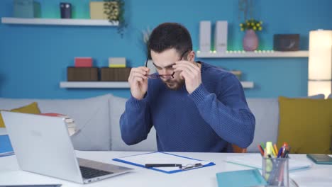 Der-Mann-Im-Homeoffice-Kann-Den-Text-Auf-Dem-Laptop-Nicht-Lesen,-Weil-Er-Müde-Ist-Und-Mit-Brille-Weiterarbeitet.