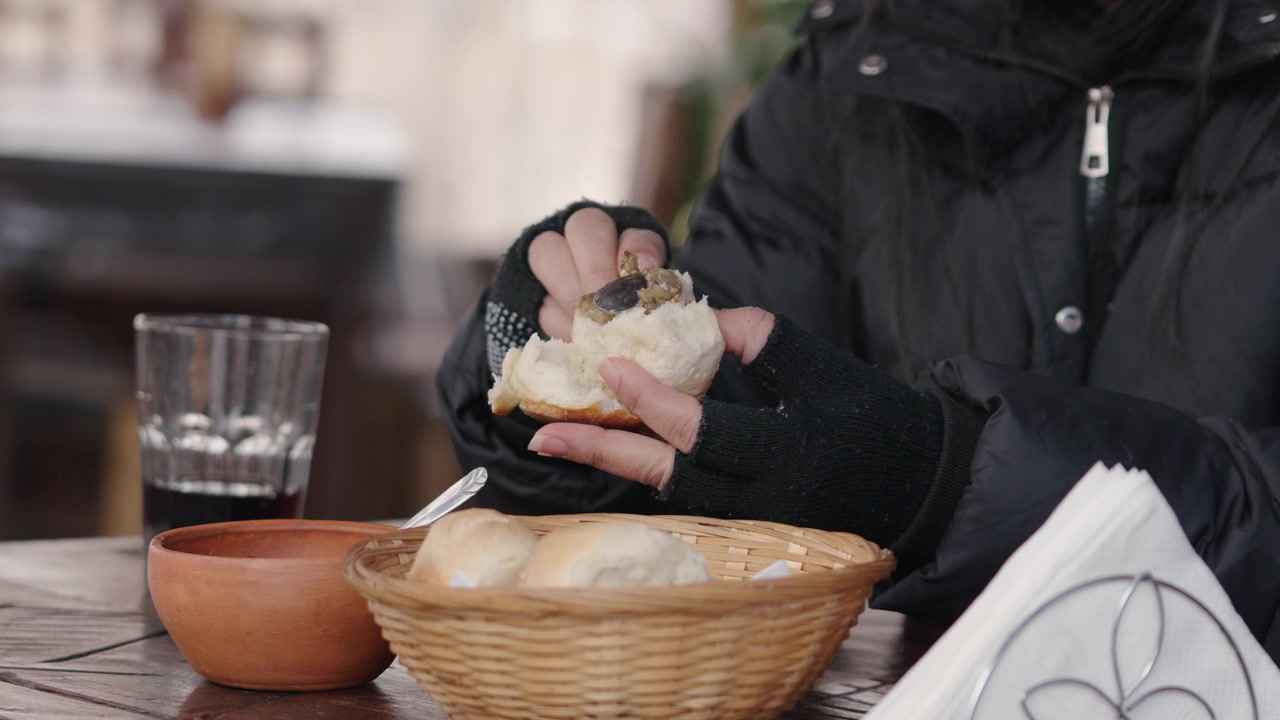 Una persona che indossa guanti spalma la marmellata su pane appena sfornato su un tavolo all'aperto. Ideale per l'uso in blog di cucina o contenuti culinari.