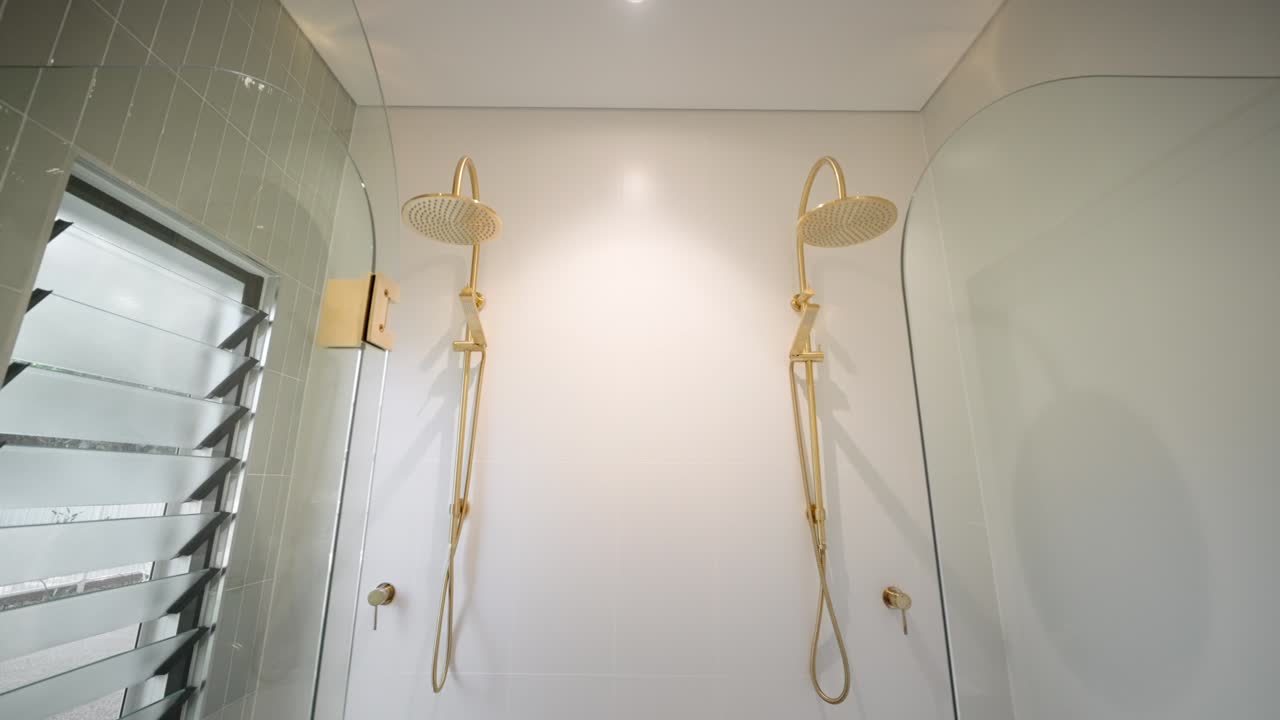 elegante baño moderno con dos cabezas de ducha de oro en una pequeña casa de lujo, mostrando accesorios elegantes