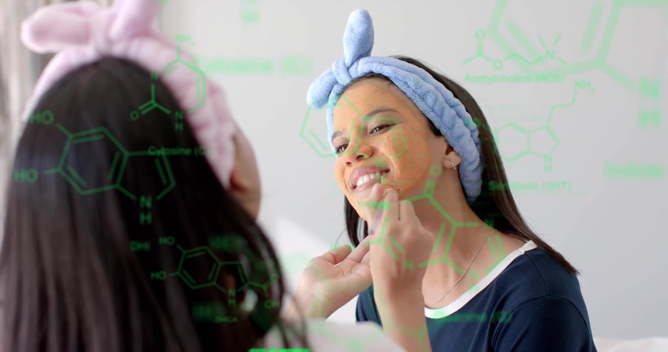 Adolescente che tiene il mento dell'amica allo specchio, mentre l'amica applica una crema per la cura della pelle per una pelle luminosa.