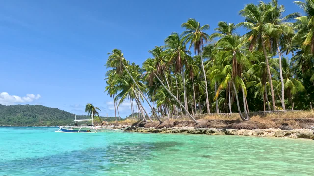 Panoramic view from the shore as the crystal clear blue ocean rolls against the coastline of a beautiful tropical island in Palawan, Philippines