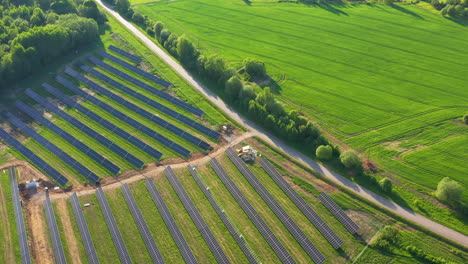 aerial view of extensive solar panel farm in countryside with golden sunlight
