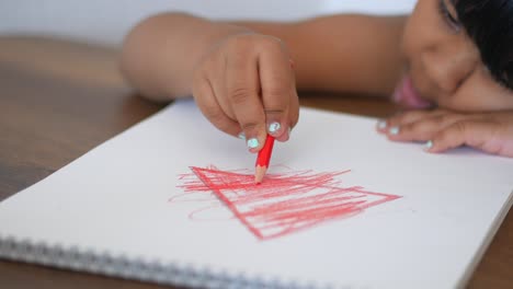 child drawing a triangle with crayon