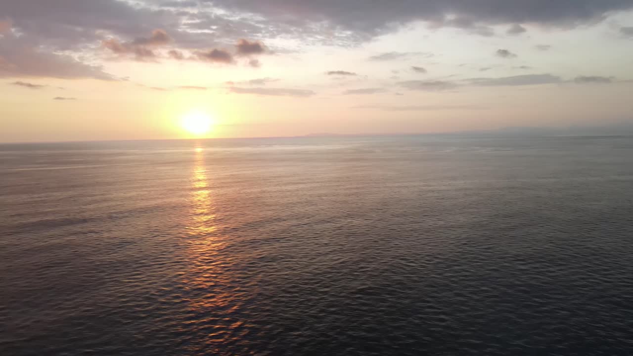 Aerial shot hovering over the sea with the sunset in the horizon