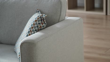 a close-up of a modern grey sofa with a patterned decorative pillow