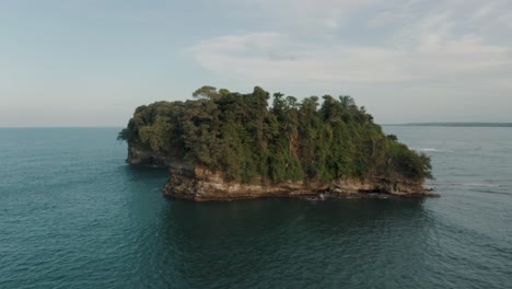 drone shot scenery of stunning sea around green rocky island with dense vegetation