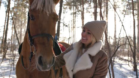 happy woman caressing horse in forest on winter day